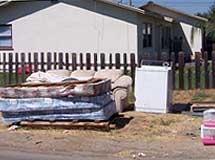 Discarded sofas and mattresses in a back yard.