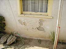 Stucco coming off a wall with water damage underneath.