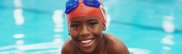 Smiling boy with goggles in a pool.